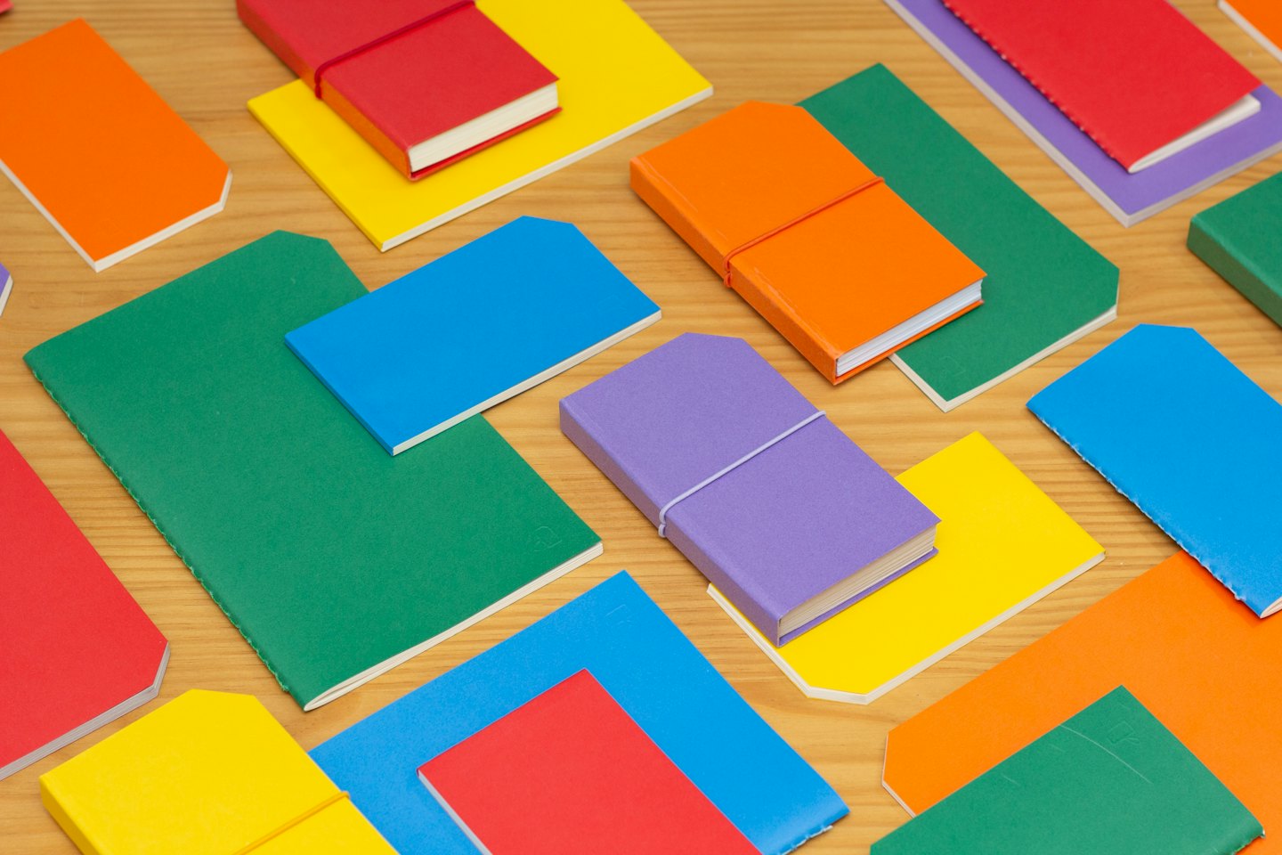 Colorful notebooks and journals scattered on a wooden table.