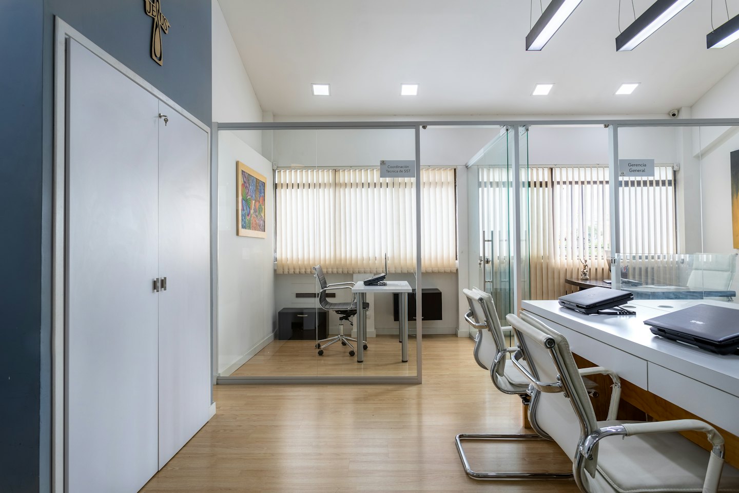 Empty modern office with glass-partitioned rooms and meeting area.